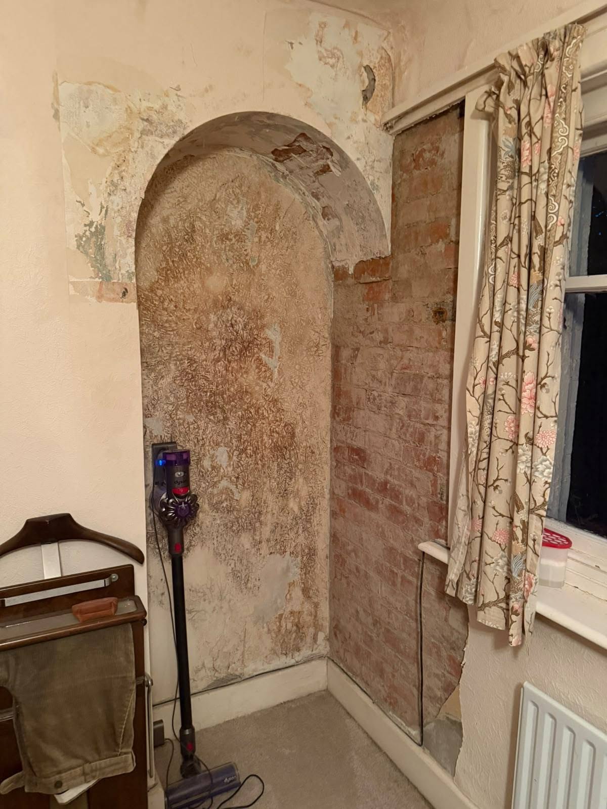 Before: an arched alcove with damaged plaster and bare brick
