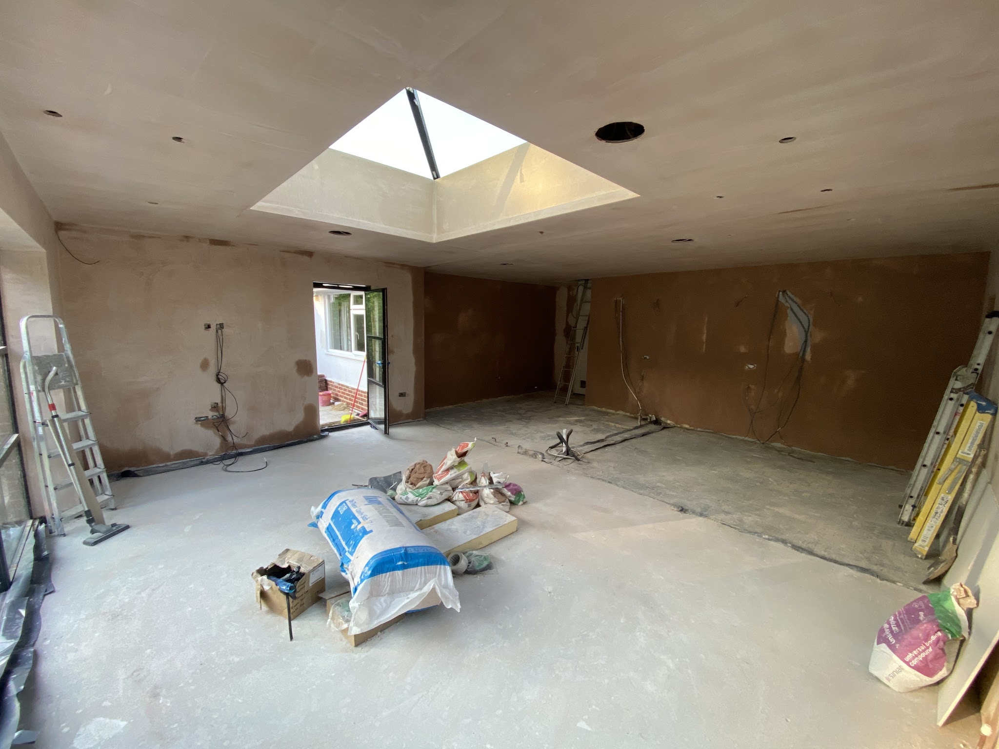 A large room under a roof lantern with walls and ceiling skimmed, materials on the floor