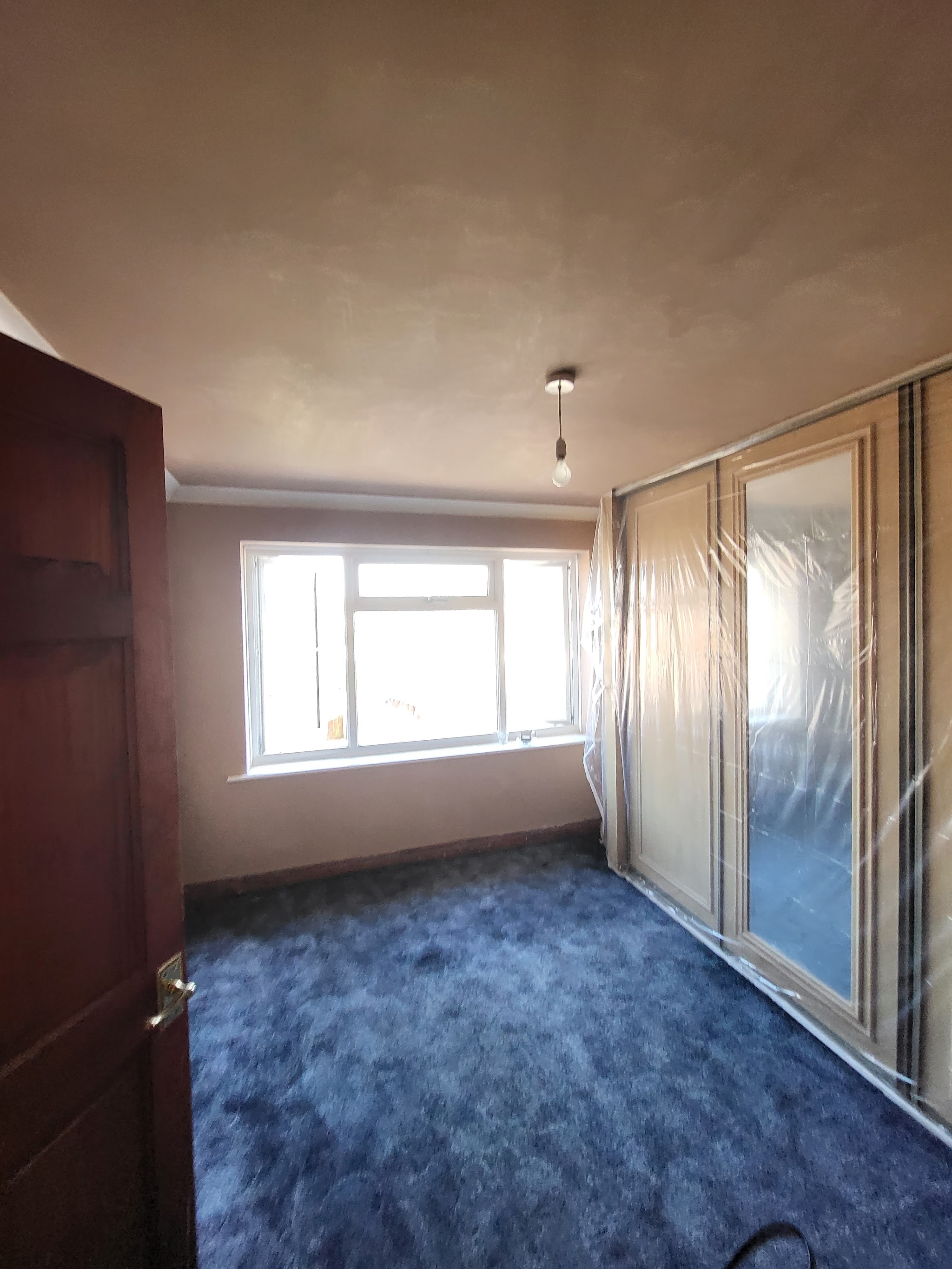 Bedroom walls and ceiling freshly plastered, dust sheets down